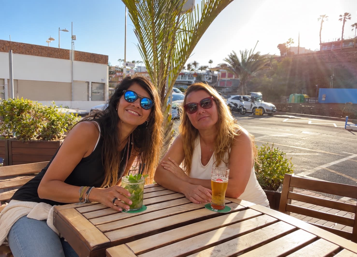 Cinthya, a la izquierda, y Alicia hoy, sentadas juntas en una terraza al sol con un mojito y una cerveza.