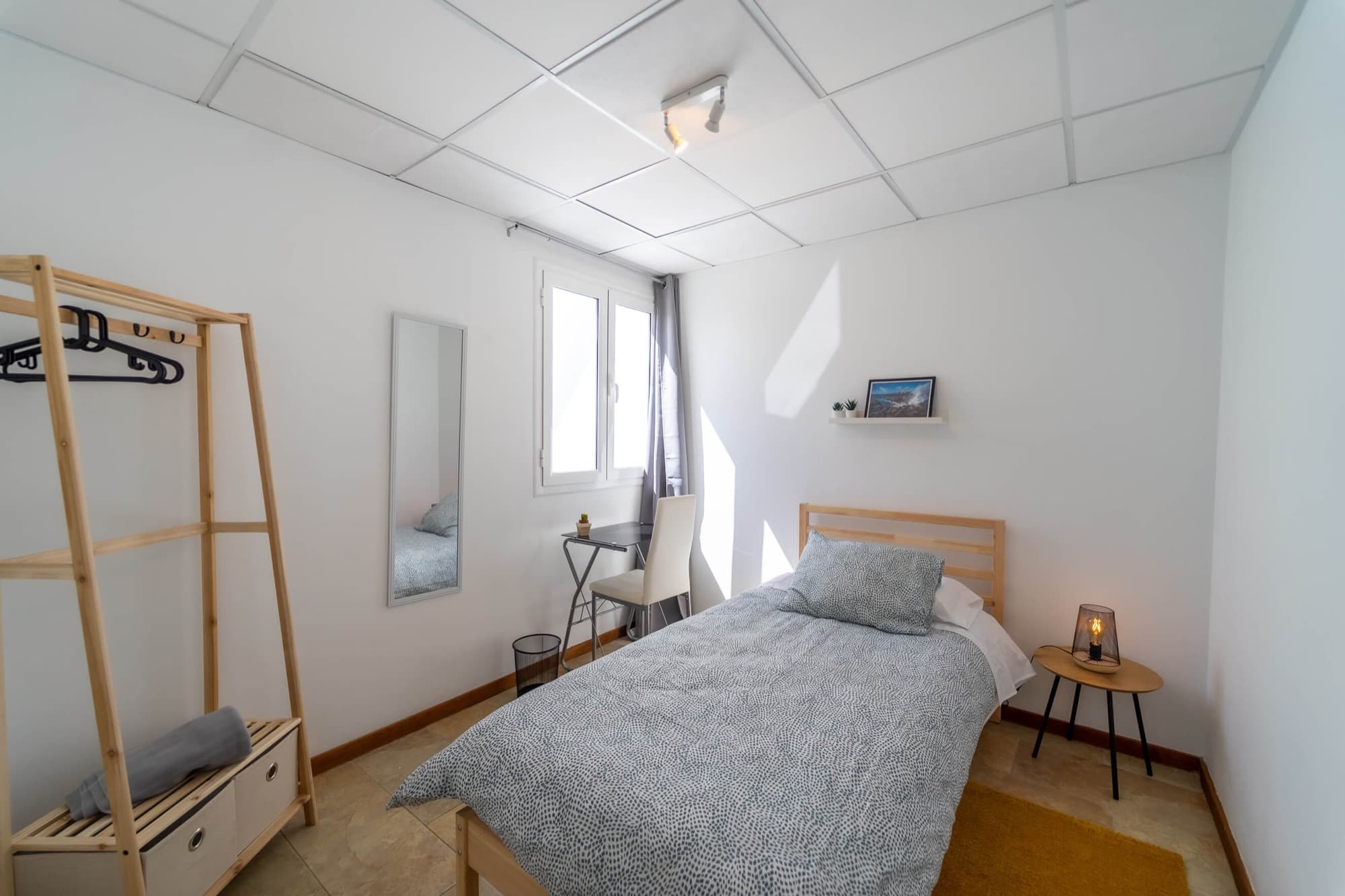Habitación Espresso: cama individual con cabecero de madera, perchero, espejo y un escritorio pequeño.