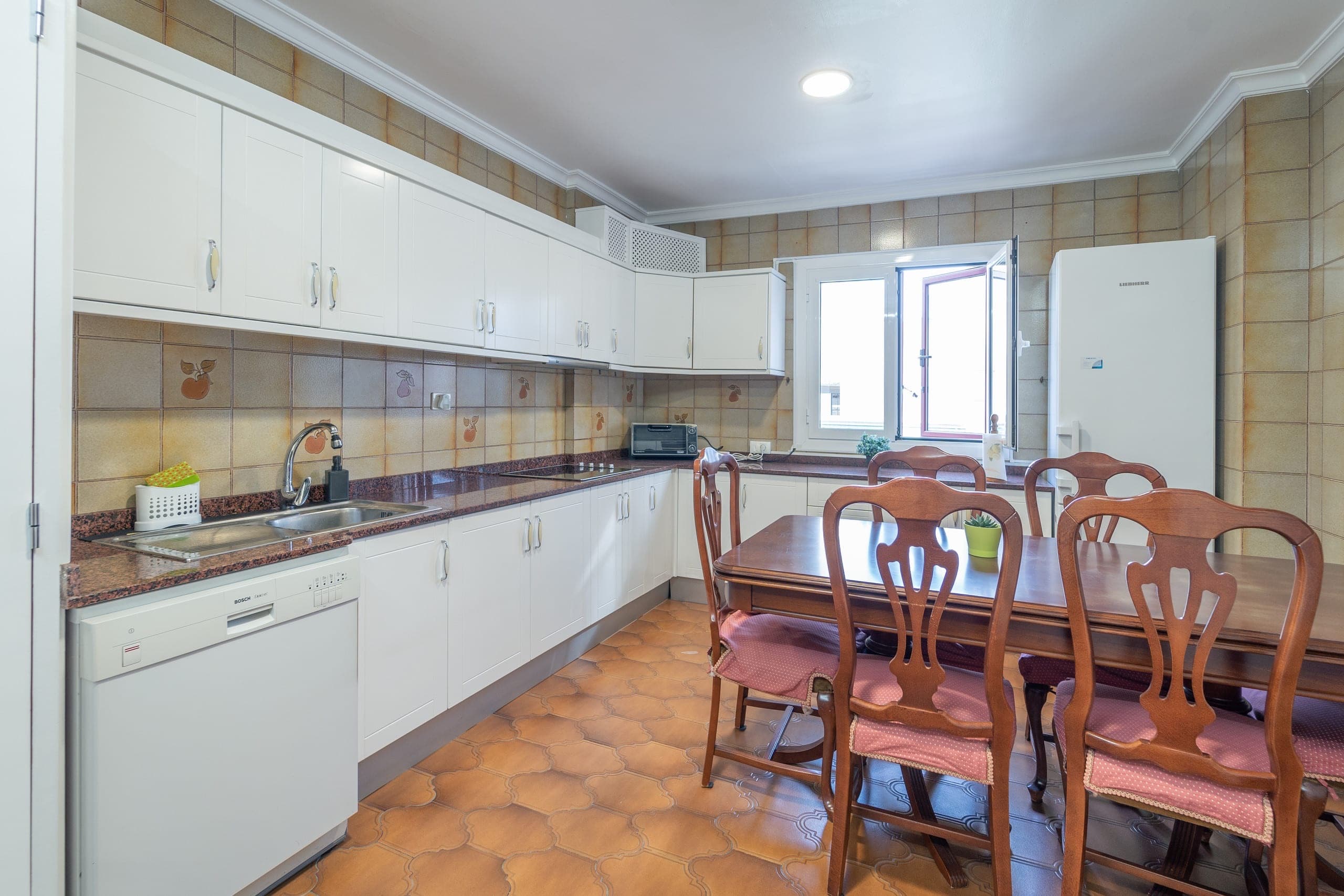 Cocina completa con muebles blancos y una mesa de comedor de madera.