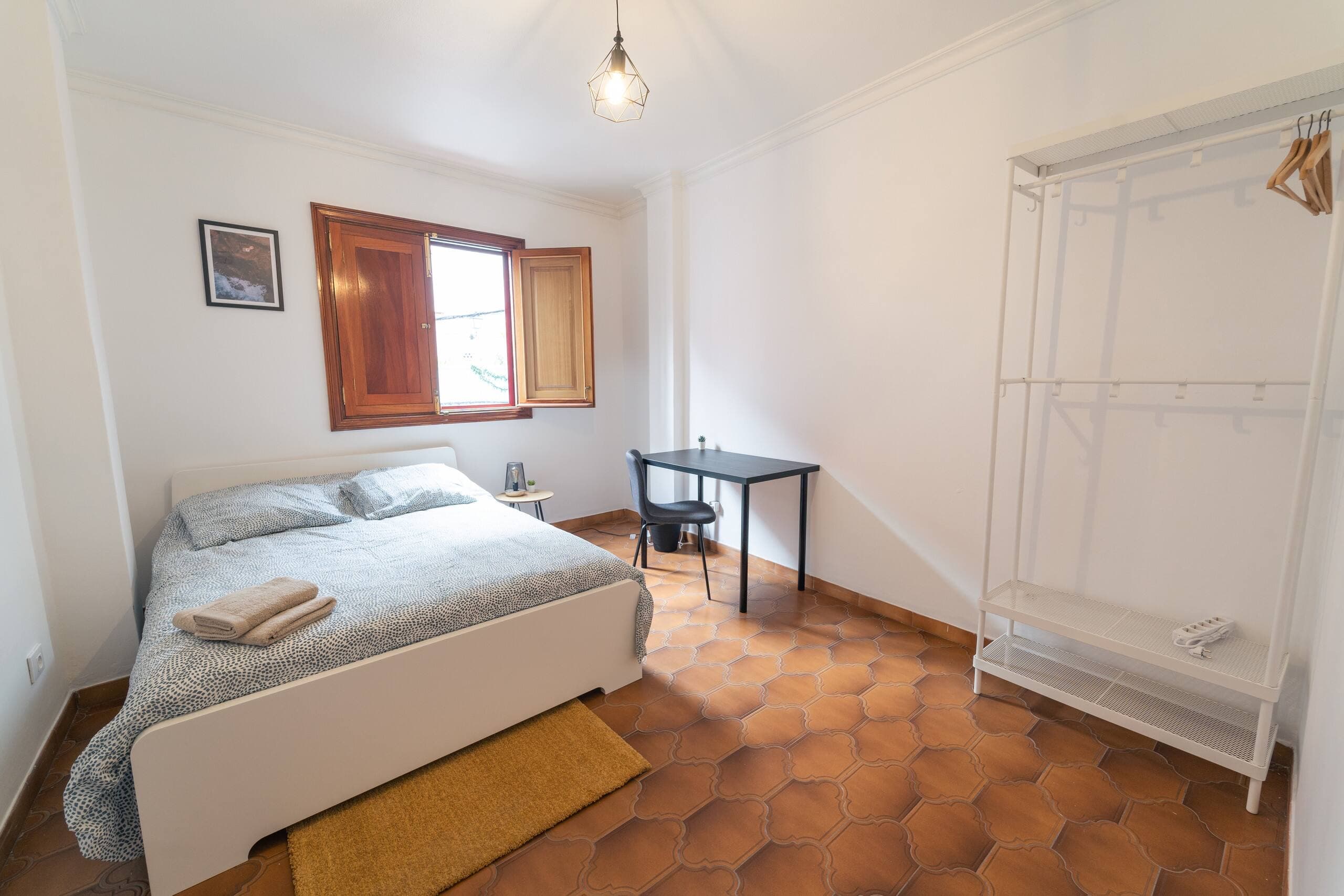 Habitación Doppio de House San Telmo: cama doble, escritorio y burro de ropa sobre suelo de barro.