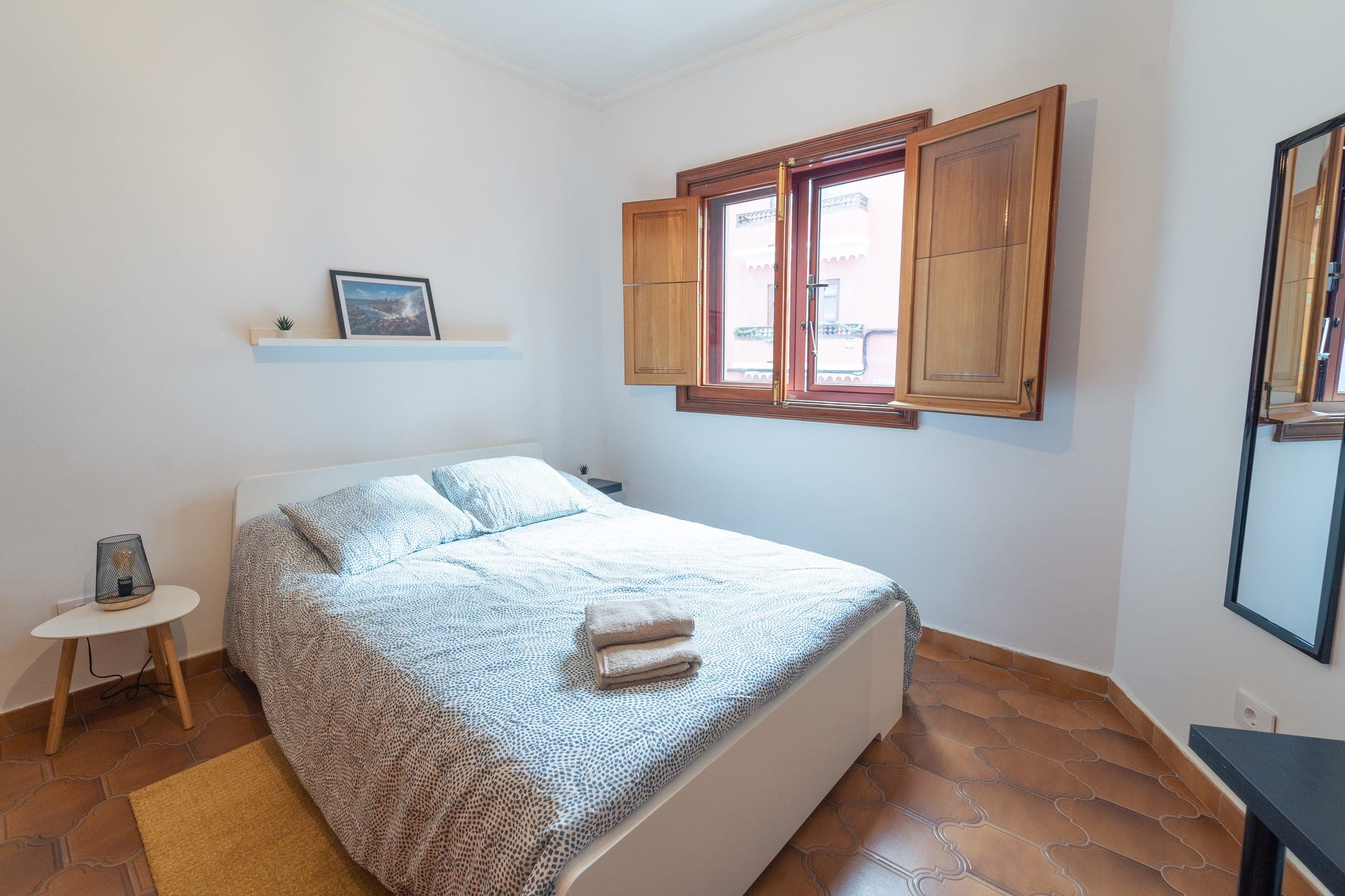 Habitación Espresso de House San Telmo: cama doble con mesilla y lámpara bajo una ventana con contraventanas de madera.