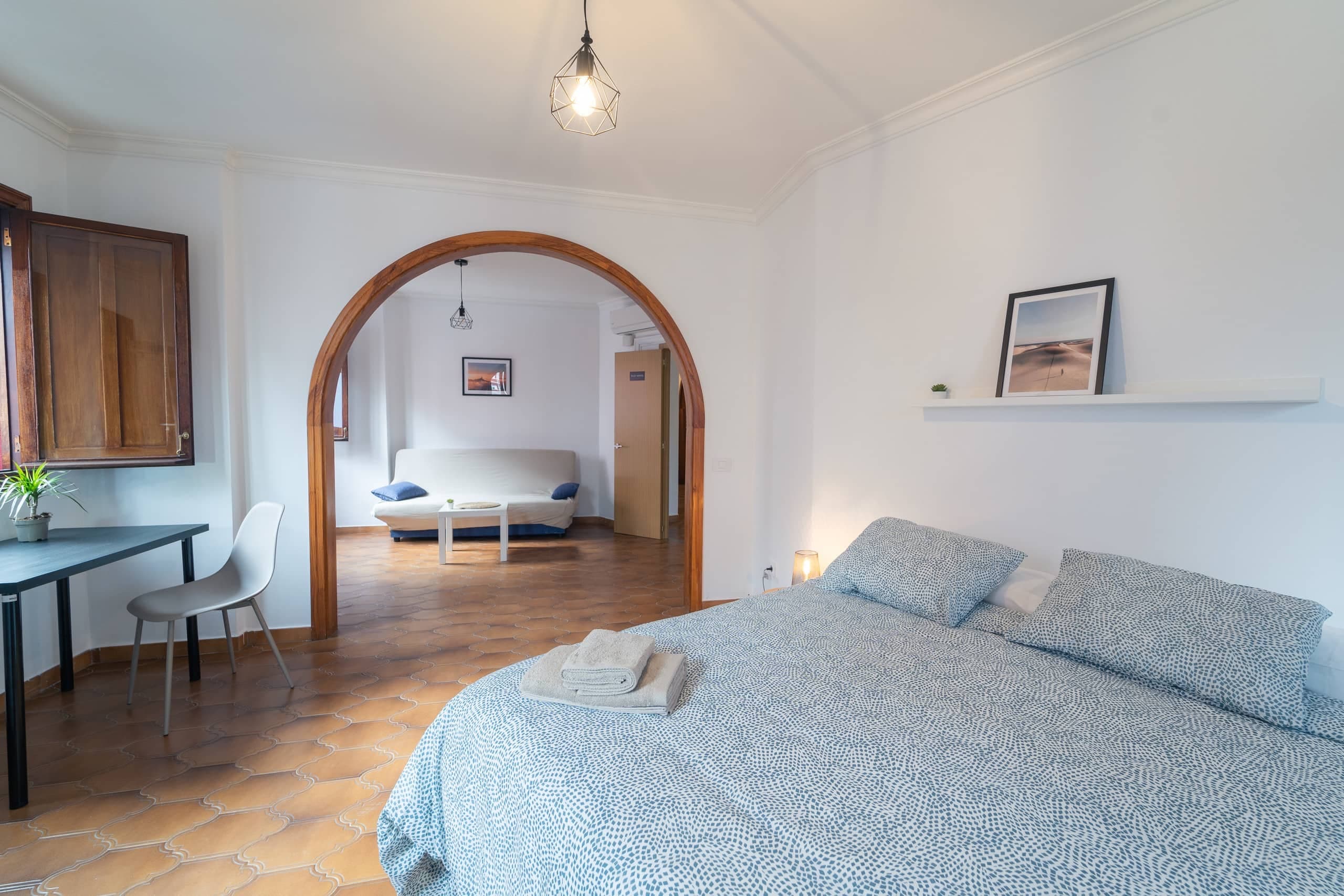 Habitación Flat White de House San Telmo: cama doble y, tras un arco de madera, una zona de estar con sofá.